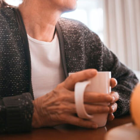 Una mujer mayor disfrutando de una taza de café.