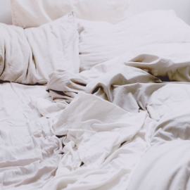 Una cama sin hacer con sábanas y almohadas blancas.