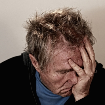 Un hombre que se siente desbordado, con las manos en la cabeza, probablemente por el estrés o la frustración.