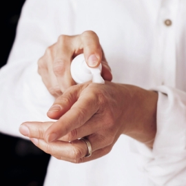 Primer plano de las manos de una mujer aplicándose crema hidratante.