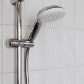 Primer plano de un cabezal de ducha del que sale agua.