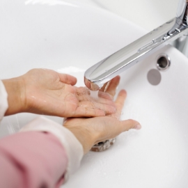 Primer plano de los brazos de una mujer lavándose las manos en un lavabo.